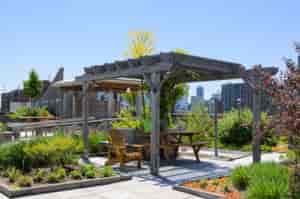 Dachterrasse mit Pflanzen und einer überdachten Sitzmöglichkeit - Garten Hennerbichler